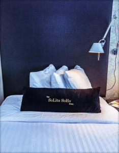 Una cama con sábanas blancas y una almohada negra. en Solita Soho Hotel, en Nueva York