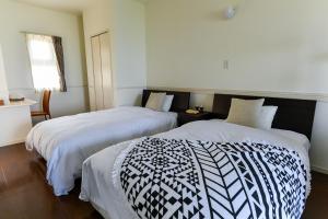 a bedroom with two beds with white and black comforters at Odysis Onna Resort Hotel in Onna