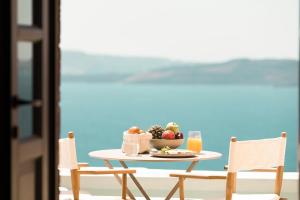 a table with a bowl of fruit and a glass of orange juice at Armenaki in Oia