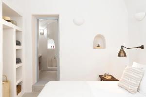 a white bedroom with a bed and a hallway at Armenaki in Oia