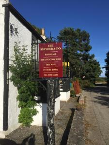 een rood bord op een paal voor een gebouw bij The Shandwick Inn in Tain