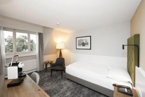 a hotel room with a bed and a desk and a chair at Hotel Löwen am See in Zug