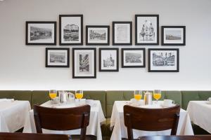 a dining room with two tables and a wall with framed pictures at Hotel Löwen am See in Zug