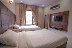 a hotel room with two beds and a television at Hillside Homes in Karachi