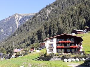 un edificio sul fianco di una collina con una montagna di Gästehaus Sahler a Gaschurn