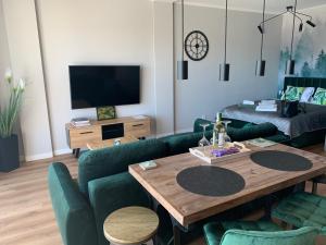 ein Wohnzimmer mit einem Tisch und grünen Stühlen in der Unterkunft Marina Green Loft-Apartament przy promenadzie in Lyck