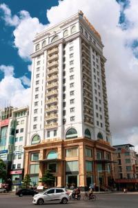 um edifício alto e branco com carros estacionados em frente em THE SHINE HOTEL em Haiphong