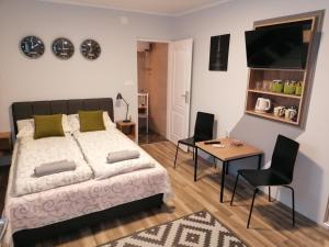 Sombor 19 Central Apartment في سومبور: غرفة نوم بسرير وطاولة وكراسي