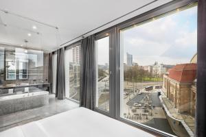 Habitación con ventanas grandes y vistas a la ciudad. en HYPERION Hotel Leipzig, en Leipzig