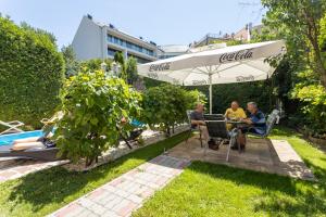 een groep mensen die aan een tafel zitten onder een paraplu bij Illés Hotel in Szeged