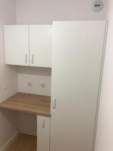 eine Küche mit weißen Schränken und einer Holztheke in der Unterkunft Nadmorskie Tarasy Apartament 312 in Kołobrzeg