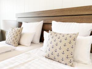 ein Bett mit weißen Kissen und einem Kopfteil aus Holz in der Unterkunft Hotel Yachtclub in Timmendorfer Strand