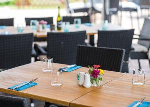 einen Holztisch mit Brille und eine Vase mit Blumen darauf in der Unterkunft Vitis Kúria 7171 Balatonrendes in Balatonrendes