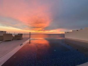 een zwembad met een zonsondergang op de achtergrond bij Okeanos Luxury Villas - Resort in Athanion