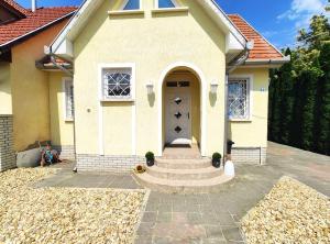 une petite maison jaune avec une porte et des escaliers dans l'établissement Apollo Vendégház, à Bogács