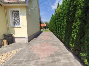 une passerelle devant une maison avec une haie dans l'établissement Apollo Vendégház, à Bogács