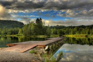 un pont en bois sur un grand lac arboré dans l'établissement Gasthof Plasch, à Ferlach