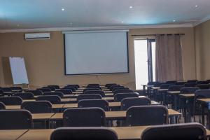 een collegezaal met tafels en stoelen en een scherm bij Coyotes Hotel & Conference Centre in Nelspruit