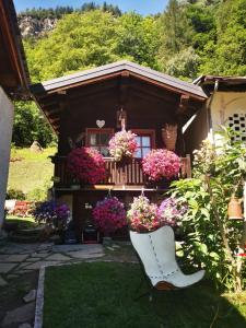 een witte stoel voor een huis met bloemen bij Maison Le Cler in Valtournenche