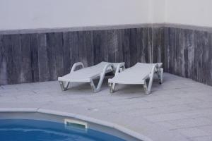 two chairs and a table next to a pool at Casinha das Bonecas - Casa com Piscina Privada in Aveiro