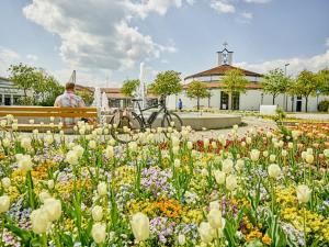 Ein Mann, der auf einer Bank in einem Garten mit Blumen sitzt. in der Unterkunft Ferienwohnung Wolfgang Halbinger in Bad Griesbach