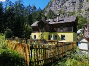 une maison avec une clôture en bois en face d'une montagne dans l'établissement Haus Waldbach, à Hallstatt