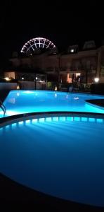 a swimming pool at night with a ferris wheel in the background at B&C Apartments in Lido di Jesolo