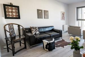 - un salon avec un canapé en cuir et une chaise dans l'établissement CLASSY APARTMENTS - Gdańsk - Widok z Wyspy, à Gdańsk