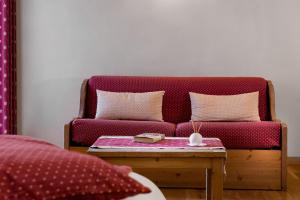 eine rote Couch in einem Zimmer mit einem Tisch in der Unterkunft Locanda Bellevue in Pré-Saint-Didier