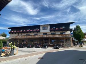 un grande edificio con macchine parcheggiate di fronte di Tennenwirt Hotel & Guesthouse a Söll