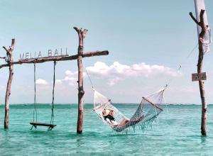 a woman is sitting in a hammock in the ocean at Meliá Bali in Nusa Dua