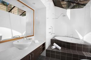 a bathroom with a sink and a tub and a mirror at BreakFree Aanuka Beach Resort in Coffs Harbour