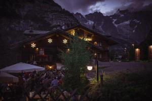 een groep mensen die 's nachts buiten een gebouw zitten bij Chalet-hotel Svizzero in Courmayeur