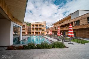 einen Pool mit Stühlen und Sonnenschirmen neben einem Gebäude in der Unterkunft Tirol Lodge in Ellmau