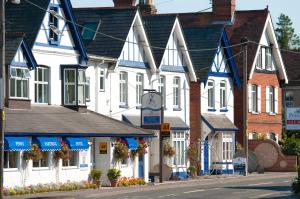 a row of white houses with blue accents on a street at Penny Farthing Hotel & Cottages in Lyndhurst