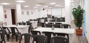 a conference room with tables and chairs and a screen at Domocenter Apartamentos Turísticos in Bormujos