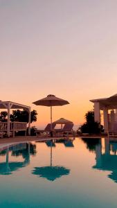 a pool with an umbrella and tables and chairs at Krotiri Bay -adults only in Parikia