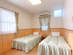 twee bedden in een kamer met houten wanden en een raam bij Lake Villa Kawaguchiko in Fujikawaguchiko