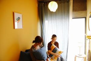 高松市にあるSUNNY DAY HOSTELの窓際のソファに座る女性2人