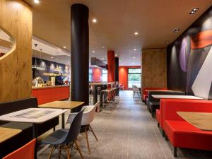 un restaurant avec des tables et des chaises rouges et noires dans l'établissement ibis Regensburg Zentrum, à Ratisbonne