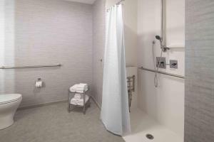 La salle de bains blanche est pourvue d'une douche et de toilettes. dans l'établissement Staybridge Suites - Boston Logan Airport - Revere, an IHG Hotel, à Revere