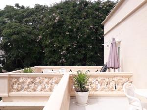 - un balcon blanc avec des chaises blanches et un parasol dans l'établissement Hotel Noucentista, à Sitges