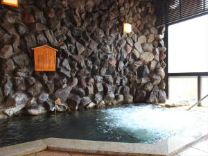 a rock wall with a pool of water in front at Ryokan Biyunoyado in Yamanouchi