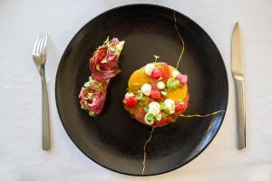 a black plate topped with food on top of bacon at Villa Florentine in Lyon