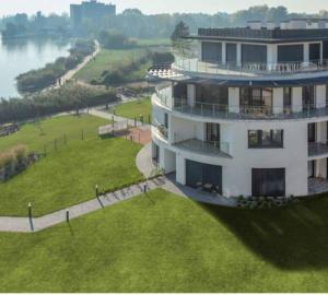 um grande edifício branco com um relvado verde junto a um rio em Balatonparti Gyöngyszem em Keszthely