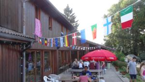 een groep mensen die aan tafels buiten een gebouw zitten bij Auberge de Jeunesse HI Annecy in Annecy