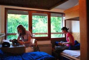 twee vrouwen zitten in een kamer met een bed bij Auberge de Jeunesse HI Annecy in Annecy