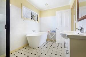 ein weißes Badezimmer mit einer Badewanne und einem Waschbecken in der Unterkunft Clifftop Apartments Portland Vic in Portland