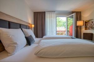 - une chambre avec un grand lit blanc et une fenêtre dans l'établissement Sporthotel Bad Bevensen, à Bad Bevensen