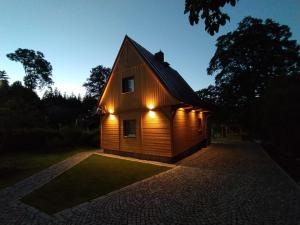 a wooden house with lights on the side of it at Sosnowa Chata - dom z prywatną sauną in Szklarska Poręba